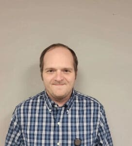 A man in a blue and white shirt is smiling.