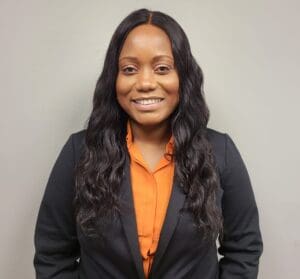 A woman in an orange shirt and black jacket